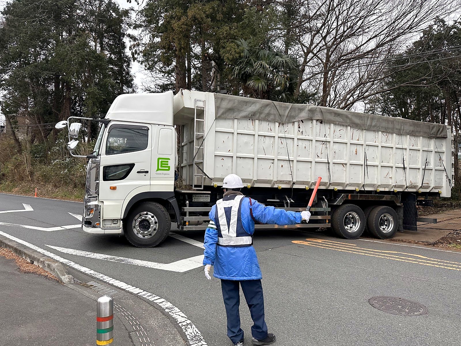道路脇の伐採現場で交通誘導をする作業員
